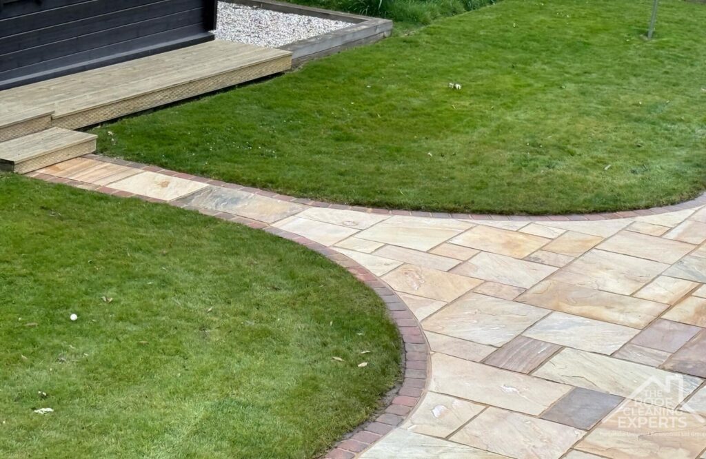 Patio with small path between two patches of lawn after patio cleaning by The Roof Cleaning Experts