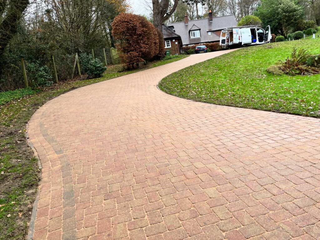 A clean, freshly restored brick driveway leading to a home, representing the quality service provided by professional driveway cleaning companies.