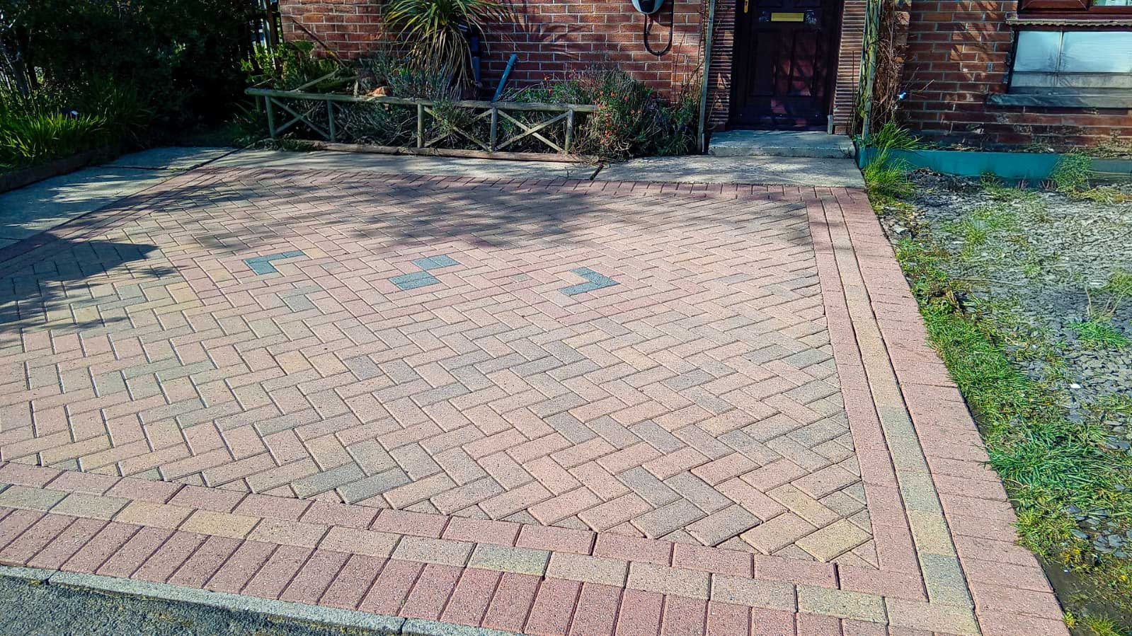 Clean brick driveway in front of a residential home, demonstrating the work of professional driveway cleaning companies.
